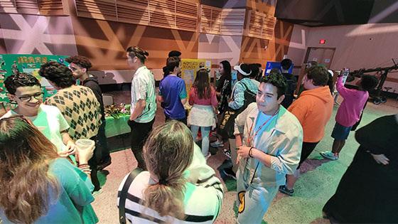 A crowd of people standing and talking around booths representing different countries at the Cultural Festival.